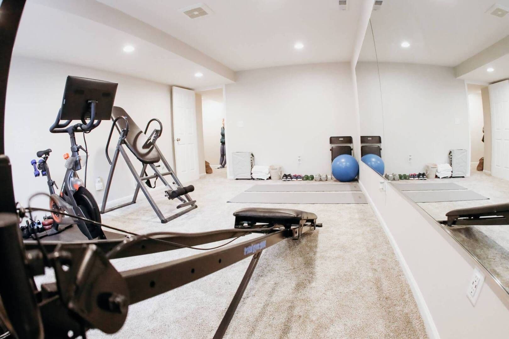 wide shot of new gym room with brand new carpeting, walls and ceiling, overhead lighting with a big wall mirror facing gym equipment