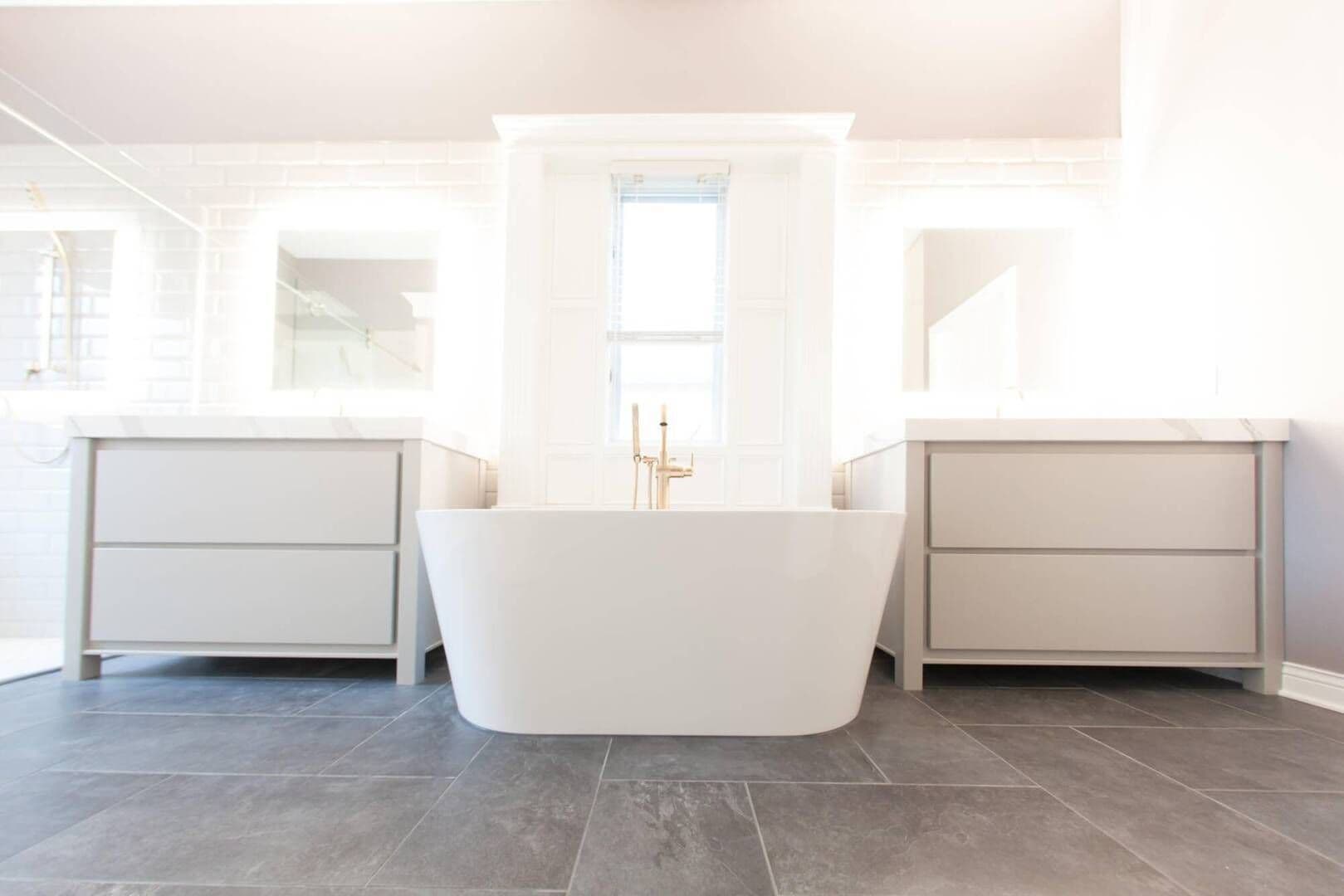 master bathroom with a drop-in bathtub between a his and her vanity