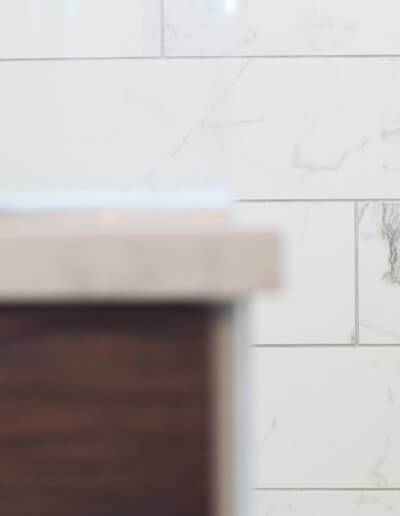 The edge of a new counter top with a marble white wall in the background.