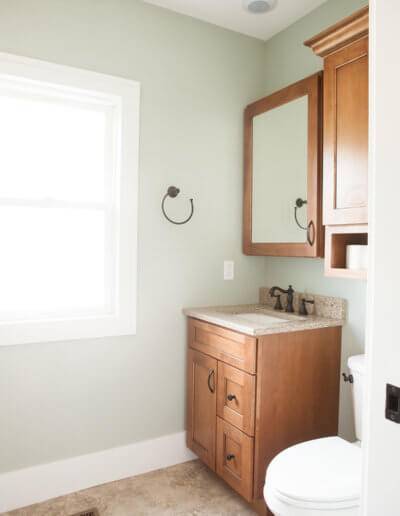 bathroom sink and mirror placed in the corner with a window letting in natural light