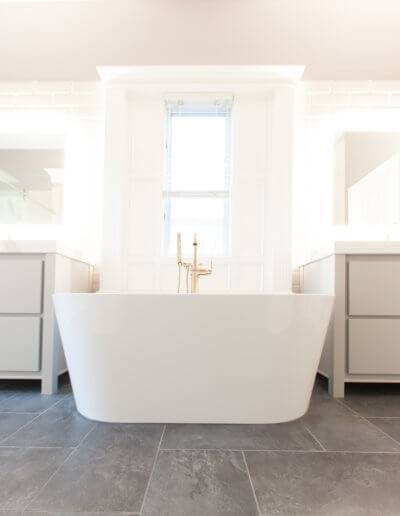 master bathroom with a drop-in bathtub between a his and her vanity