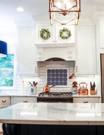 wide shot of finished rennovated kitchen with white cabinets, marble countertops and blue/white china