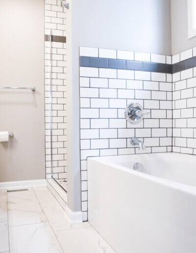 angled from the floor and across bathroom. White bathtub to the right with black and white tiled backsplash