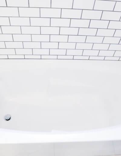 top, down view of white bathtub with white and black subway tile surrounding and silver fixtures