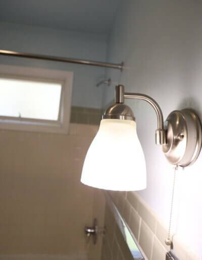 up close image of silver bathroom light fixture about countertop from the side
